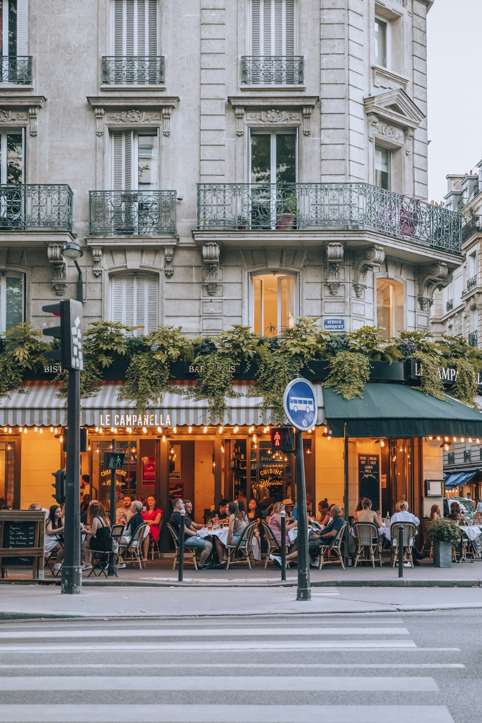 A sunny foreign neighbourhood street with warm light, cafés and life